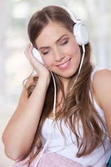 Portrait of a beautiful young woman listening to music with clos
