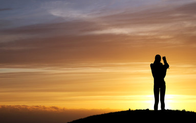 Fototapeta na wymiar silhouette of female photographer in sunset