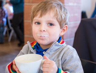 Little toddler boy drinking cup of milk