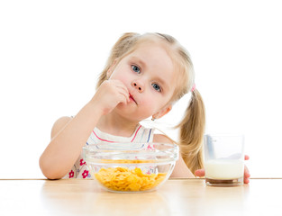 kid girl eating corn flakes with milk over white