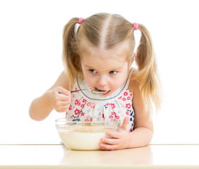 child girl eating corn flakes with milk over white