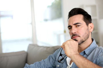 Man sitting in sofa with thoughtful look on his face