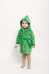 Portrait of a cheerful baby boy with blue eyes in green bathrobe