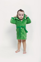 Portrait of a cheerful baby boy with blue eyes in green bathrobe