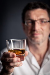 Erwachsener Mann hält ein alkoholisches Getränk in der Hand