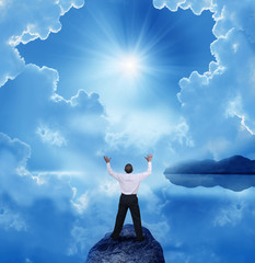 businessman standing with open arms on a rock