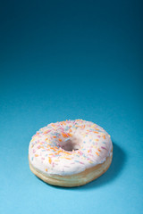 donut with white icing isolated on blue background with copyspac