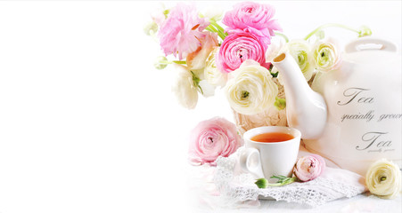A cup of tea with teapot and ranunculus