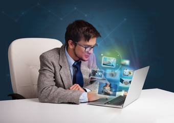Young man sitting at desk and watching his photo gallery on lapt