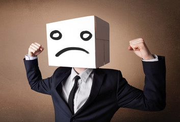 Businessman gesturing with cardboard box on his head with sad fa