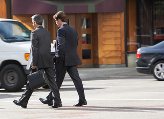 Obraz premium Two Businessman Chatting Whilst Crossing Street