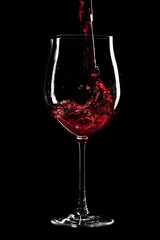 Red wine being poured into a glass infront of black background