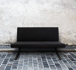 modern sofa on cobblestone street with wall behind