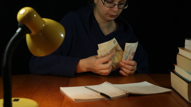 Woman in bathrobe counting money at night