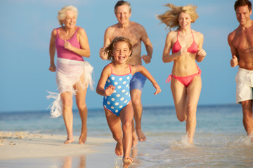 Multi Generation Family Having Fun In Sea On Beach Holiday