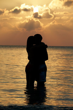 Silhouette Of Romantic Couple Standing In Sea
