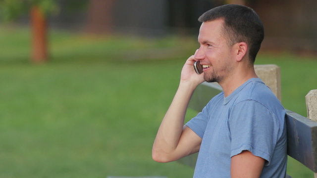Man talks on the phone on a park bench