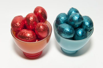Colored chocolate Easter eggs in glass cups of the same color