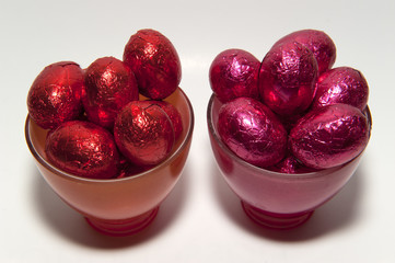 Colored chocolate Easter eggs in glass cups of the same color