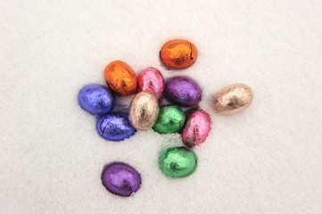 Colorful chocolate Easter eggs in a snowy white background