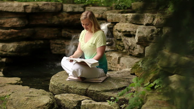 Woman reading near a waterfall