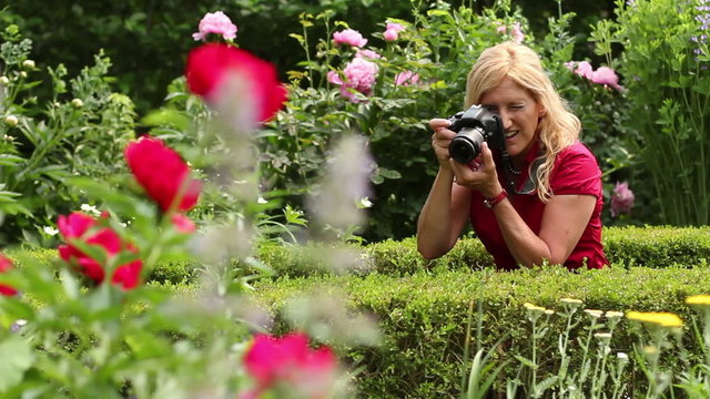 Blond woman taking pictures of flowers