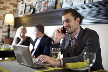 The businessman using the laptop and mobile in cafe.