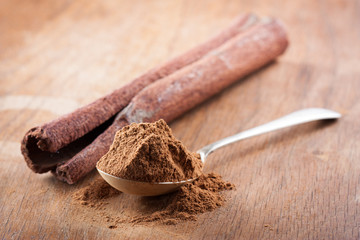 Cinnamon powder on a spoon with a stick of natural cinnamon