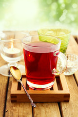 Glass of herbal tea on wooden table over bokeh background