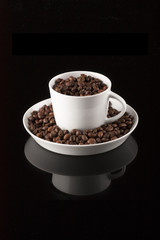 Obraz na płótnie Canvas Coffee mug filled with coffee on black reflective surface