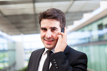 Closeup portrait of smiling young business man using cell phone
