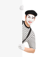 Smiling mime artist posing behind a blank panel