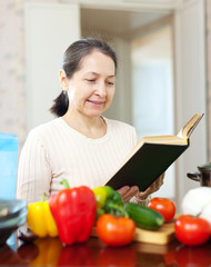   woman reads cookbook for recipe in kitchen