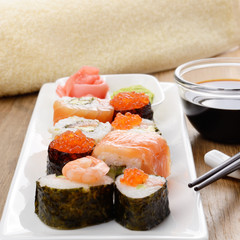 Mixed sushi on a white plate with soy sauce wasabi and ginger