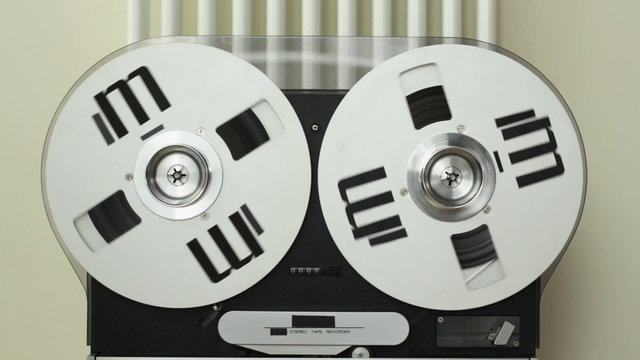 Reel to reel tape playing on a tape machine, close up