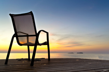 Chair on a pier near the sea during sunrise