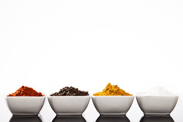 reihe kleiner schälchen mit paprika pfeffer curry und salz