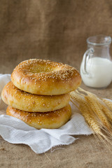 Three fresh pitas bread, ears of rye and milk jug.