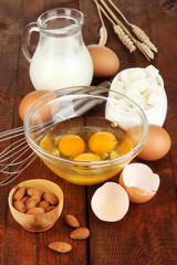 Broken egg in bowl and various ingredients next to them