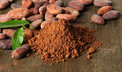 Cocoa beans and cocoa powder on wooden background