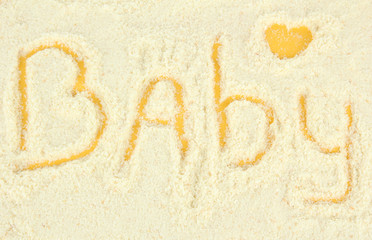 Word baby making with powdered milk on yellow background