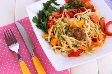 Noodles with vegetables on plate on wooden table