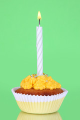 Beautiful cupcake with candle on green background