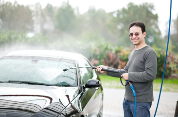 Young man washing his car with compression water