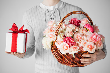 man holding basket full of flowers and gift box