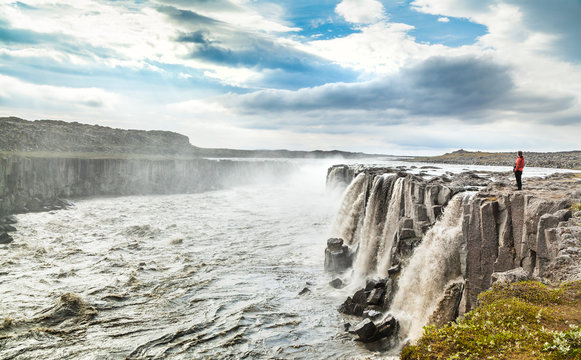 Woman standing near famous Dettifoss waterfall in Iceland