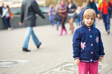 Small sad girl standing on the street