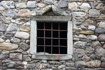 Fototapeta na wymiar window with a metal grid on an old stone barn