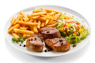 Grilled steaks, French fries and vegetables