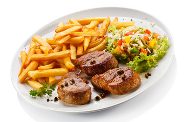 Grilled steaks, French fries and vegetables